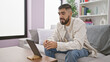 © Krakenimages.com - Handsome man using tablet on couch indoors with bookshelf decor