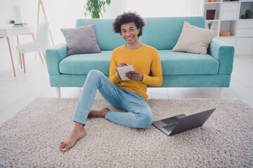 Canvas Print - Full length portrait of nice young man sit carpet laptop notepad wear pullover white interior flat indoors