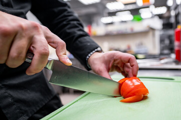 Wall Mural - Close-up of hands slicing a tomato on a green cutting board