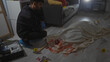 © Krakenimages.com - Hispanic man analyzing bloodstained scene with evidence markers in dimly lit apartment living room
