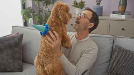 Poster - A middle-aged man joyfully interacts with his playful poodle in a cozy, modern living room.