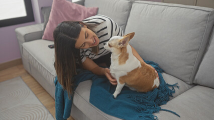 Canvas Print - A smiling young woman enjoys a moment with her pet chihuahua on a couch in a cozy living room setting.