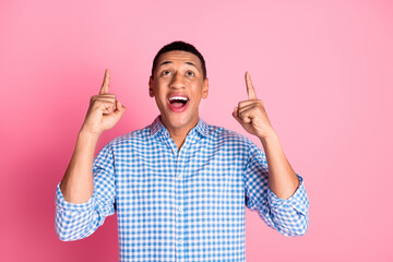 Photo of handsome good mood guy wear plaid shirt showing two fingers up emtpy space isolated pink color background