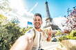 © Davide Angelini - Happy tourist taking selfie picture in front of Eiffel Tower in Paris, France - Travel and summer vacation life style concept
