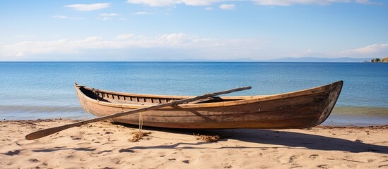 Poster - Wooden canoe resting on the sandy beach with a clear view of the ocean in the background, ideal for adding text or design in the copy space image.