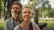 © iuricazac - A man and woman possibly a couple sitting in a park smiling with trees and a blurred background suggesting a peaceful outdoor setting.