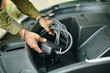 © DragonImages - Hands of owner putting charging cable in trunk of hybrid car