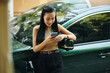 © DragonImages - Elegant smiling young woman leaning on electric car, waiting for charging