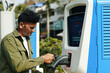 © DragonImages - Driver taking plug from public ev charging station