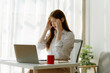 © Nittaya - Asian women are stressed while working on laptop, Tired asian businesswoman with headache at office, feeling sick at work, copy space