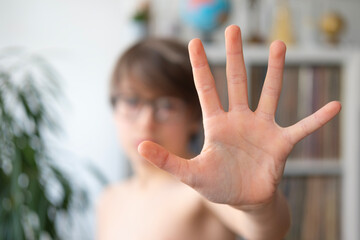 Child, 11-year-old boy extending hand to signal stop, stopping gesture, alert action, complains about domestic violence, Emotional expression