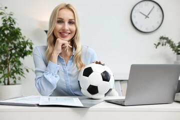 Wall Mural - Happy woman with soccer ball at table in office