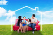 © Creativa Images - Happy family sitting on red sofa outdoor with house picture