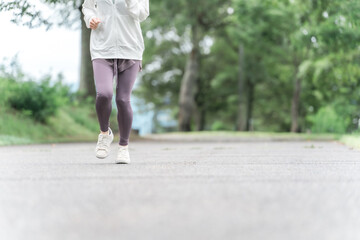 Canvas Print - ダイエット・カロリー消費のため公園でウォーキング・運動をするスポーツウェアのアジア人女性の足元
