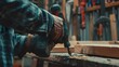 © Nature Creative - Closeup male carpenter hand in gloves using electric drill to assemble the wood in the carpentry shop