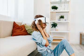 Smiling woman using virtual reality glasses at home, enjoying a futuristic VR game on the sofa