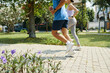 © DragonImages - Man and woman running together in a park, focusing on their fitness routine in a sunny outdoor setting