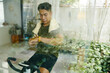 © DragonImages - A man looking at his smartwatch while sitting on a stationary bike in a modern living room with plants