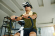 © DragonImages - A man using a VR headset while exercising on a stationary bike in a modern living space with a relaxed atmosphere