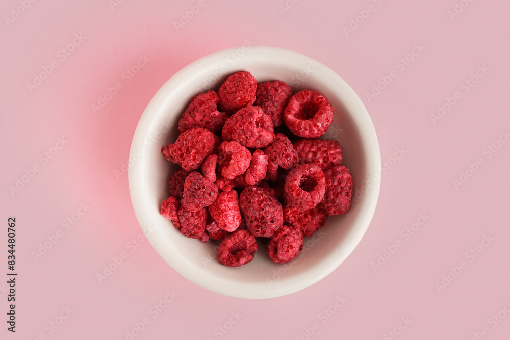 Bowl with freeze-dried raspberries on pink background