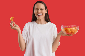 Canvas Print - Young woman with bowl of potato chips on red background