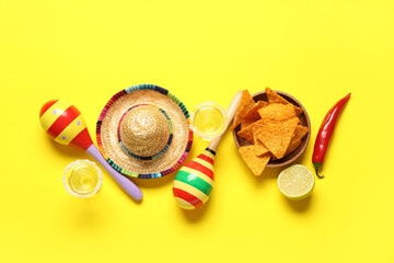 Mexican maracas with sombrero, nachos and tequila on yellow background. Cinco de Mayo