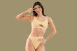 © Pixel-Shot - Young woman in swimsuit showing victory gesture on green background