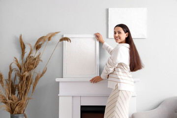 Sticker - Young woman near fireplace with paintings at home