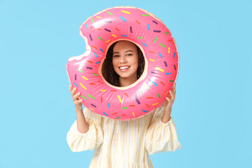 Wall Mural - Beautiful young African-American woman with inflatable ring on blue background