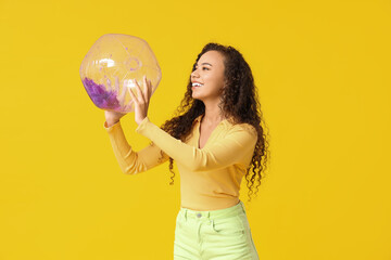 Sticker - Beautiful young African-American woman with beach ball on yellow background