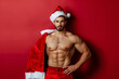 © lashkhidzetim - A man with a Santa hat on his head. He is posing for a picture. The man is muscular and has a beard