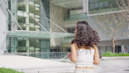 Wall Mural - Charming young asian woman running in the urban city square and turn back smile at camera, lovely Chinese girlfriend