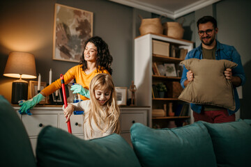 Cheerful family bonding while organizing and cleaning their living room.