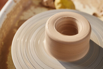 Wall Mural - Minimal close up of carefully shaped raw clay on pottery wheel lit by sunlight copy space