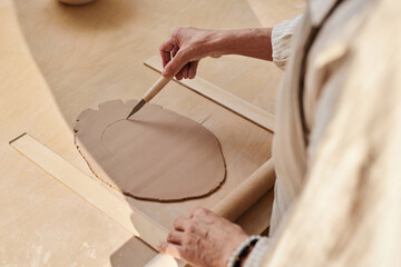 Wall Mural - Minimal closeup of female hands carefully decorating clay piece in pottery studio copy space