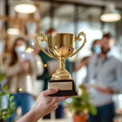 New win award trophy of Victorious business team in office environment, holding aloft a gleaming gold trophy, colleagues cheering and applauding in blurred background.