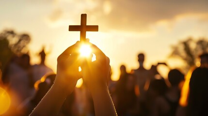 Silhouette of a cross held up against the sunset during a gathering of people, symbolizing faith and unity.