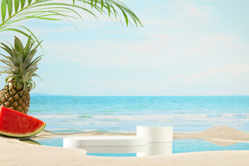 Photo of the summer seaside with frontal angle, coconut leaves and tropical fruits like pineapple and watermelon decorated in the left corner, in center of the beach has two showcase podiums