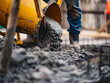 © ron - A construction worker in a hardhat operates a cement mixer to prepare fresh concrete mix.