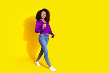 Sticker - Full body photo of attractive young woman hold paper cup walking dressed stylish violet clothes isolated on yellow color background