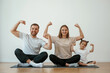 © standret - Showing the biceps, strong. Family of mother, father and daughter are doing yoga at home