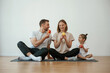 © standret - With apples in hands. Family of mother, father and daughter are doing yoga at home
