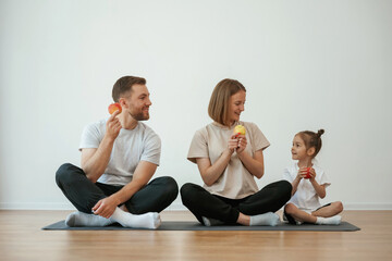 Sticker - With apples in hands. Family of mother, father and daughter are doing yoga at home