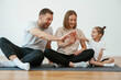 © standret - Doing high five. Family of mother, father and daughter are doing yoga at home