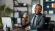 © Anna - African American male office worker in business attire, smiling while working at a desk in a bright office