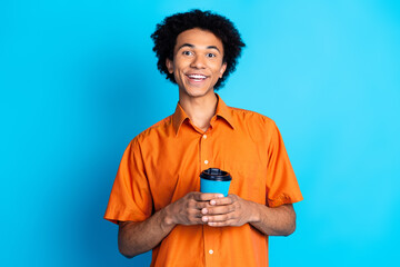 Poster - Photo of handsome good mood guy wear orange shirt drinking coffee emtpy space isolated blue color background