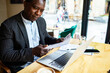 © Marko Geber - Businessman reviewing documents in a cafe with laptop