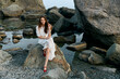 © SHOTPRIME STUDIO - Woman in white dress sitting on ocean rock with red shoes, gazing at the horizon