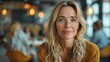 © Vilaysack - Portrait of a serene woman with glasses in a cozy cafe, surrounded by warm lighting and blurred background of people enjoying their time.