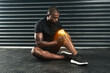 © peopleimages.com - Fitness, injury and black man with knee pain on floor for sports accident, strain or muscle fatigue. Leg, overlay and athlete with exercise emergency for swollen tendon, inflammation or medical issue